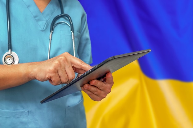 Surgeon or doctor using a digital tablet on the background of the Ukraine flag