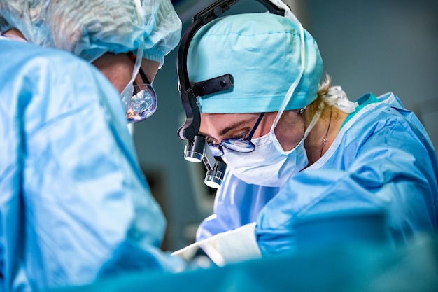 Surgeon and his assistant performing cosmetic surgery on nose in hospital operating room Nose reshaping augmentation Rhinoplasty