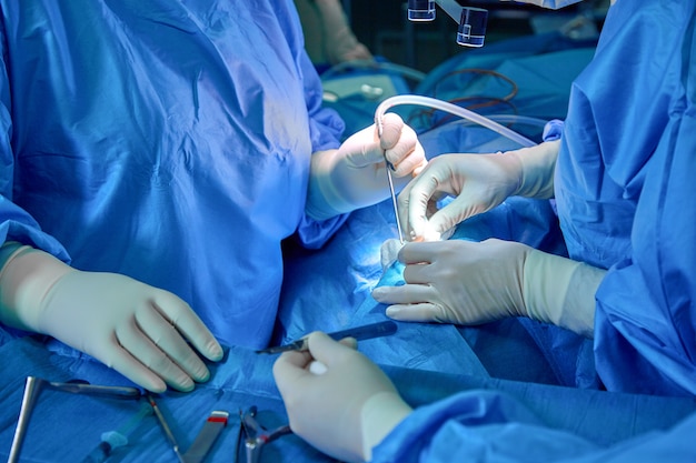 Surgeon and his assistant performing cosmetic surgery on nose in hospital operating room.