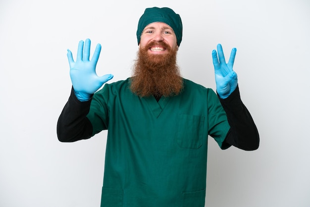 Surgeon redhead man in green uniform isolated on white background counting eight with fingers