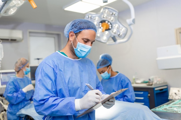 Surgeon writing on clipboard in operation room anaesthesiologist writing the updates