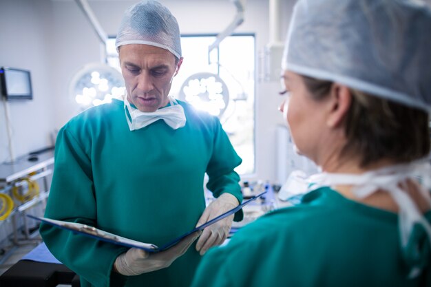 Surgeons discussing over medical reports in operation room