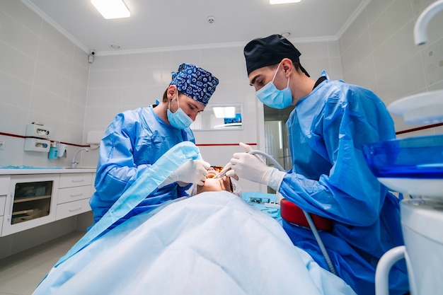 Surgery dental operation. Two dentists provide stomatology operation. Dental clinic. Selective focus.