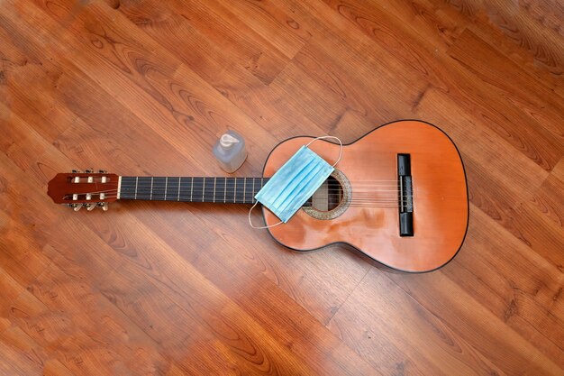 A surgical mask and an antiseptic dispenser next to a Spanish guitar