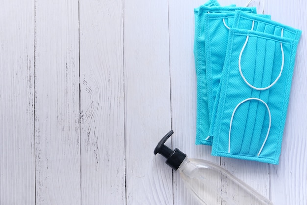 Surgical mask and sanitizer on wooden table