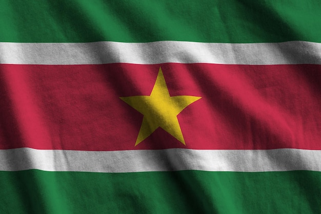 Suriname flag with big folds waving close up under the studio light indoors The official symbols and colors in banner