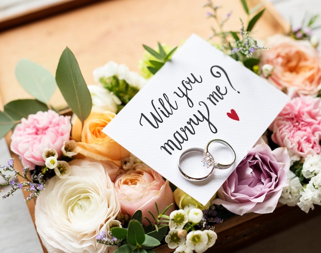 Photo a surprise marriage proposal with will you marry me card and rings