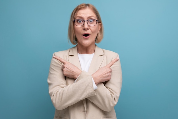 Surprised adult woman with a bob hairstyle in a classic jacket points to the side on a bright