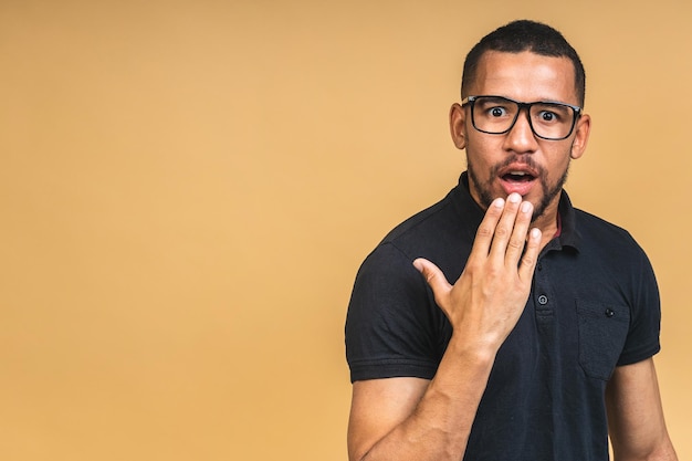 Surprised amazed shocked african american man guy in casual isolated over beige background studio portrait People lifestyle concept Mock up copy space Keeping mouth open