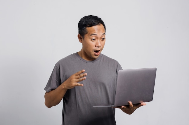 Surprised Asian man looking at laptop