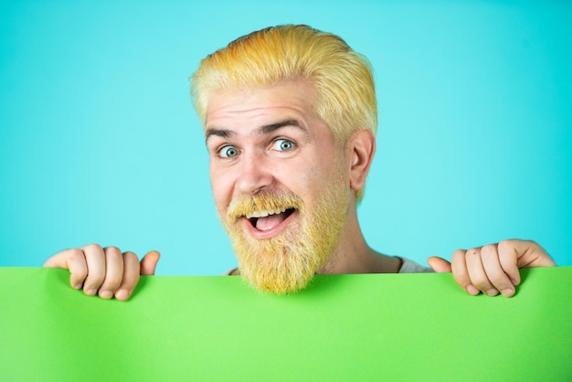 Surprised bearded man holding empty paper blank empty paper billboard with copy space for text