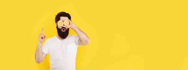 Surprised bearded man holding lemon slices in front of eyes