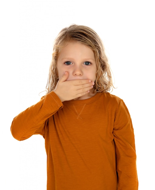 Surprised blond child with blue eyes covering his mouth