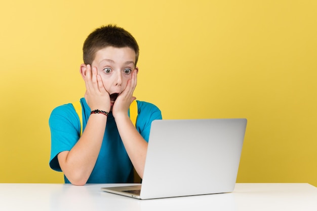 Surprised boy hands on face in front of computer