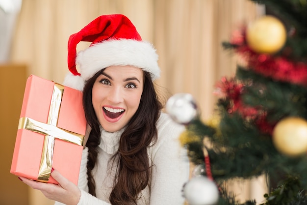 Surprised brunette holding a gift 