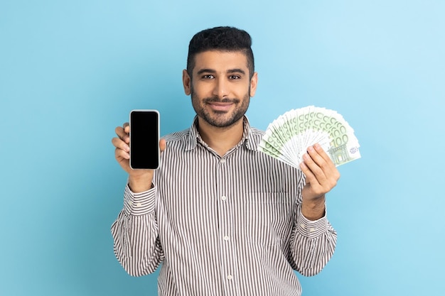 Surprised businessman with beard holding cell phone and euro banknotes shocked by money cashback