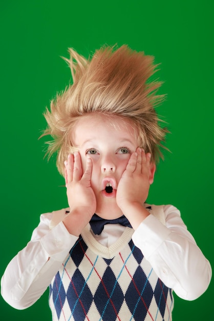 Surprised child against green chalkboard in class