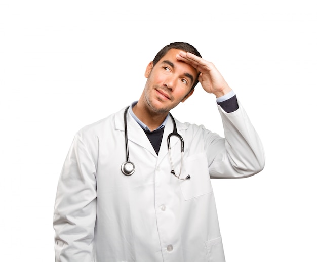 Surprised doctor with search gesture against white background