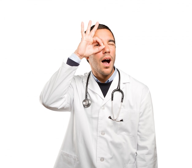 Surprised doctor with search gesture against white background