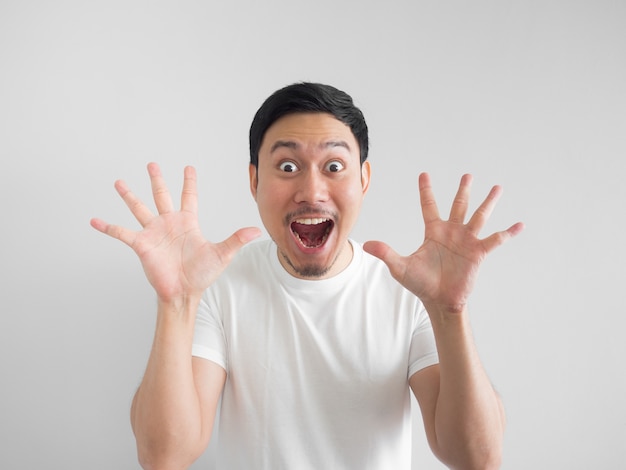 Surprised face of happy asian man in white shirt  light grey background.