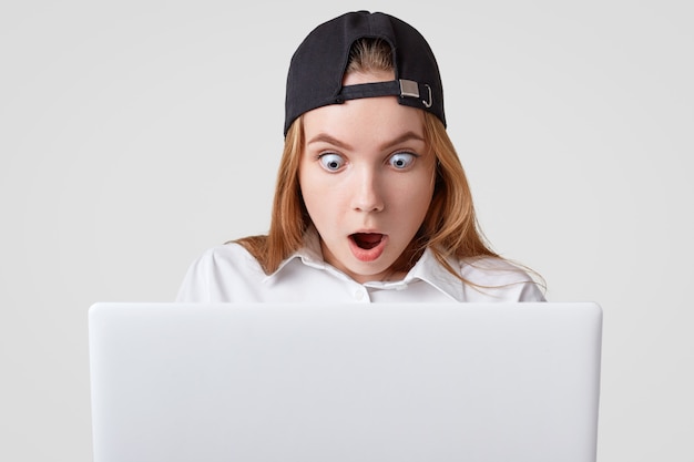 Surprised female looking into screen of laptop