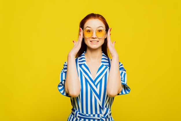 Surprised girl is on the yellow background. A girl with beautifull red hair