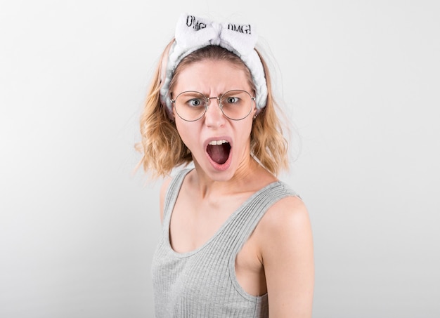 Surprised happy blonde woman in white short rejoices and looking at the camera over white