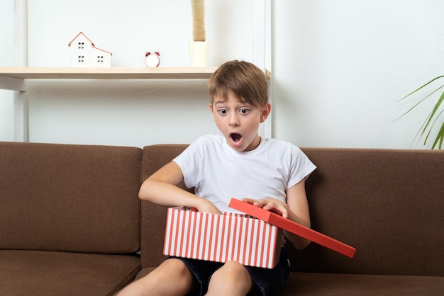 Surprised happy boy opened gift. Child with gift box with an open box in his hands.