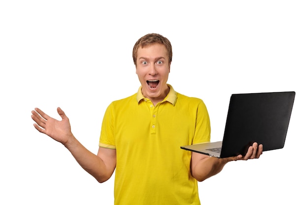 Surprised happy male with laptop in hand isolated on white background Funny shocked young man in yellow Tshirt holds notebook in hand Funny guy with happy look face due to sales discounts