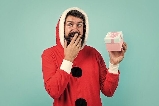 Surprised male hipster with beard and moustache wearing santa costume for xmas party celebration with gift box black friday