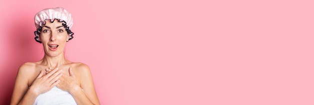 Surprised shocked young woman in pink shower cap on pink background Banner