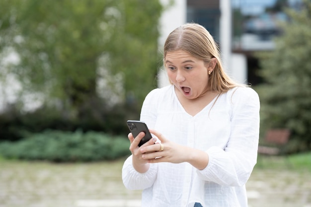 Surprised teenager girl looking at phone