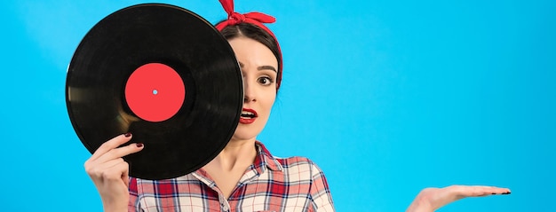 The surprised woman holding a vinyl record on the blue background