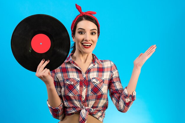 The surprised woman holding a vinyl record on the blue background