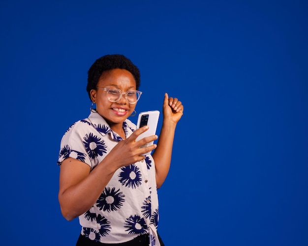 Surprised young African lady using mobile phone with positive expression