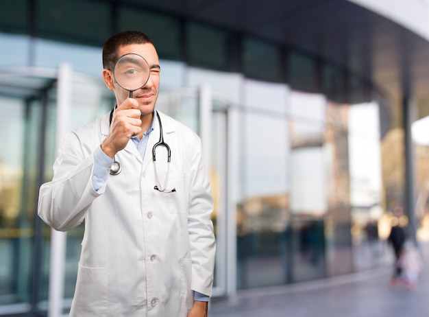 Surprised young doctor using a magnifying glass