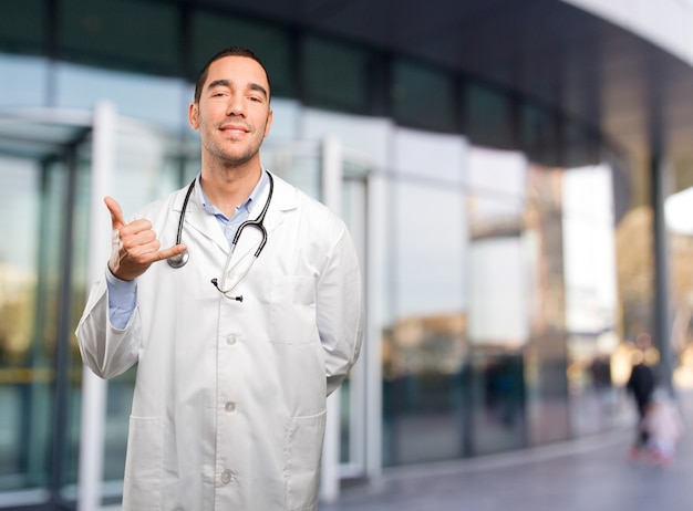 Surprised young doctor with call gesture