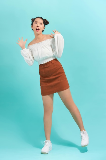 Surprised young female student over blue background Looking at camera