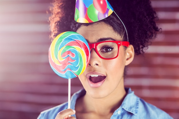 Surprised young woman holding a lollipop against her face 