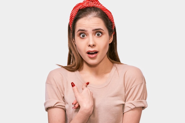 Surprised young woman looking doubtful at discussing important decisions gesturing with hand dressed in casual trendy outfit posing over white wall Student girl has confused expression