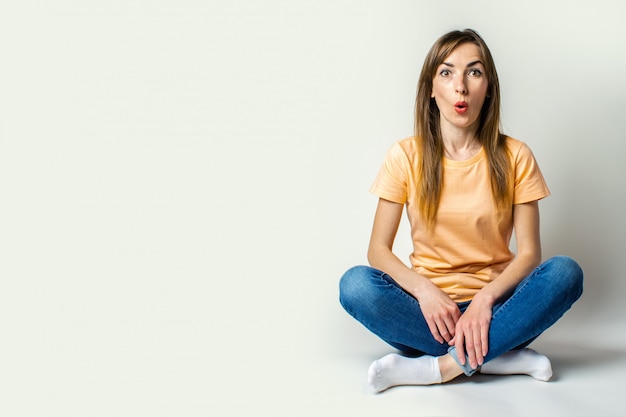 Surprised young woman sitting on the floor