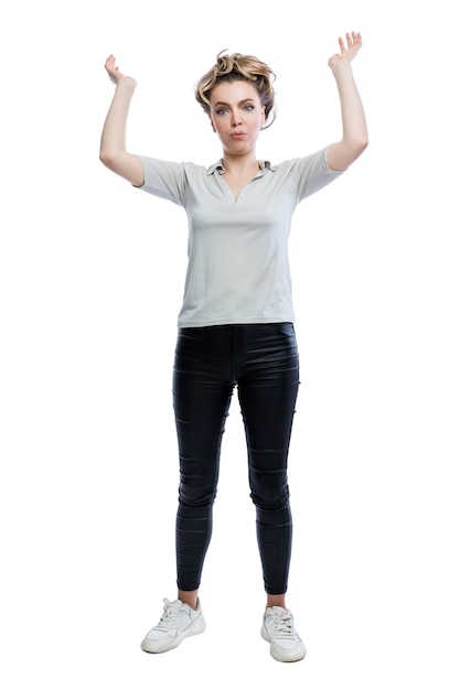 Surprised young woman with hands raised up Beautiful blonde in black leggings a gray tshirt and white sneakers Full height Surprise and amazement Isolated on white background Vertical