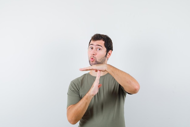 Surprising young man holding his hands perpendicular on white background