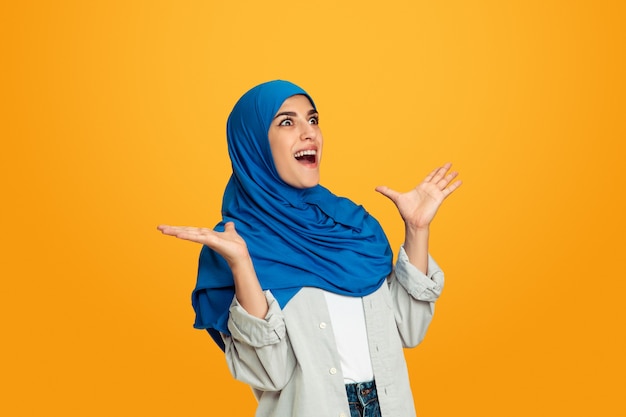 Surprising. Young muslim woman isolated on yellow