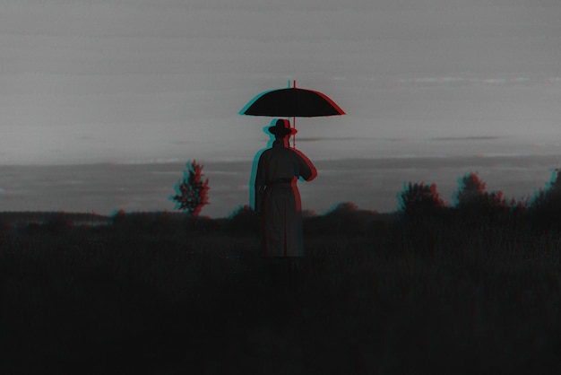 Surreal silhouette of a man in a suit with an umbrella standing in a raincoat in a field The concept of freedom