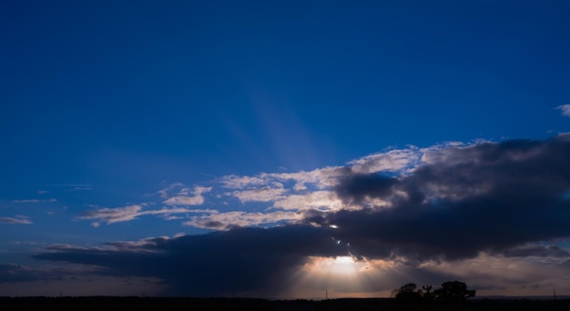 Suset sky lanscapesunlight shine through cloudscape on blue sky background Horizon beautiful sundown with silhouette high voltage electric tansportationHigh voltage transmission pole against sunset