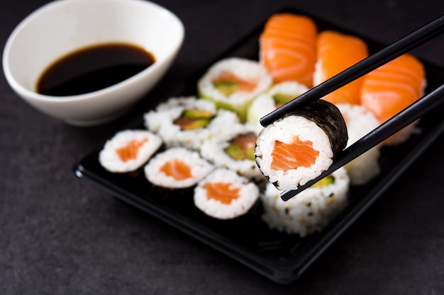 sushi assortment on black tray and soy sauce.