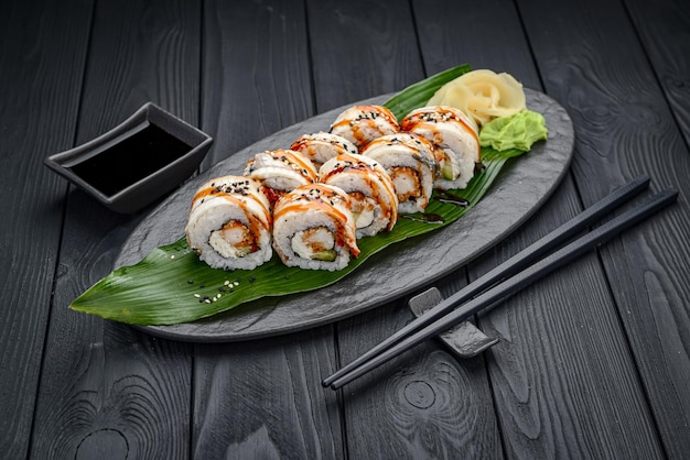 Sushi roll dragon with smoked eel and shrimp Traditional delicious fresh sushi roll set on a black background Sushi menu Japanese kitchen restaurant Asian food