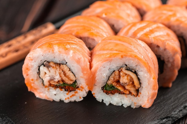 Sushi roll maguro with salmon smoked eel avocado and tobiko on black board closeup sushi menu japane