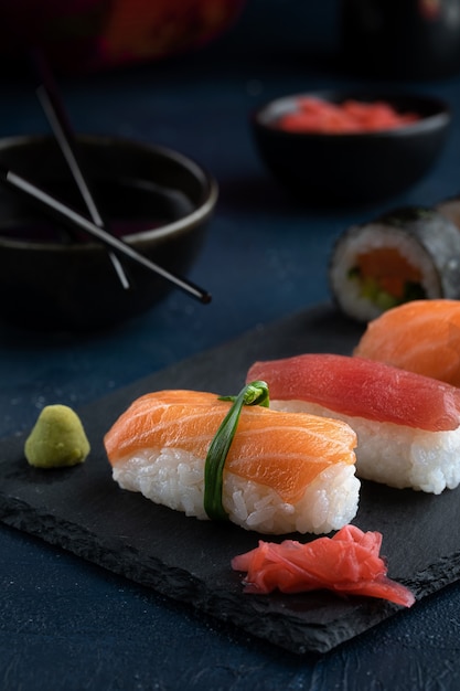 Sushi roll, nigiri with salmon, tuna, avocado and vegetables placed on black rock